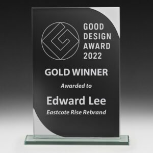 Black glass award plaque with curved silver corner detail and engraved good design winner text on clear base