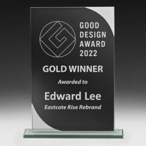 Black glass award plaque with curved silver corner detail and engraved good design winner text on clear base
