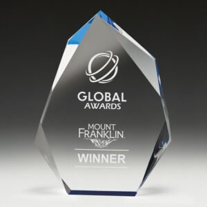 Small clear faceted crystal award with angled geometric design and subtle blue edge accents, laser engraved logo and text for corporate recognition.