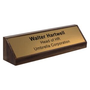 Dark timber desk name plate with engraved brass plate displaying name and job title