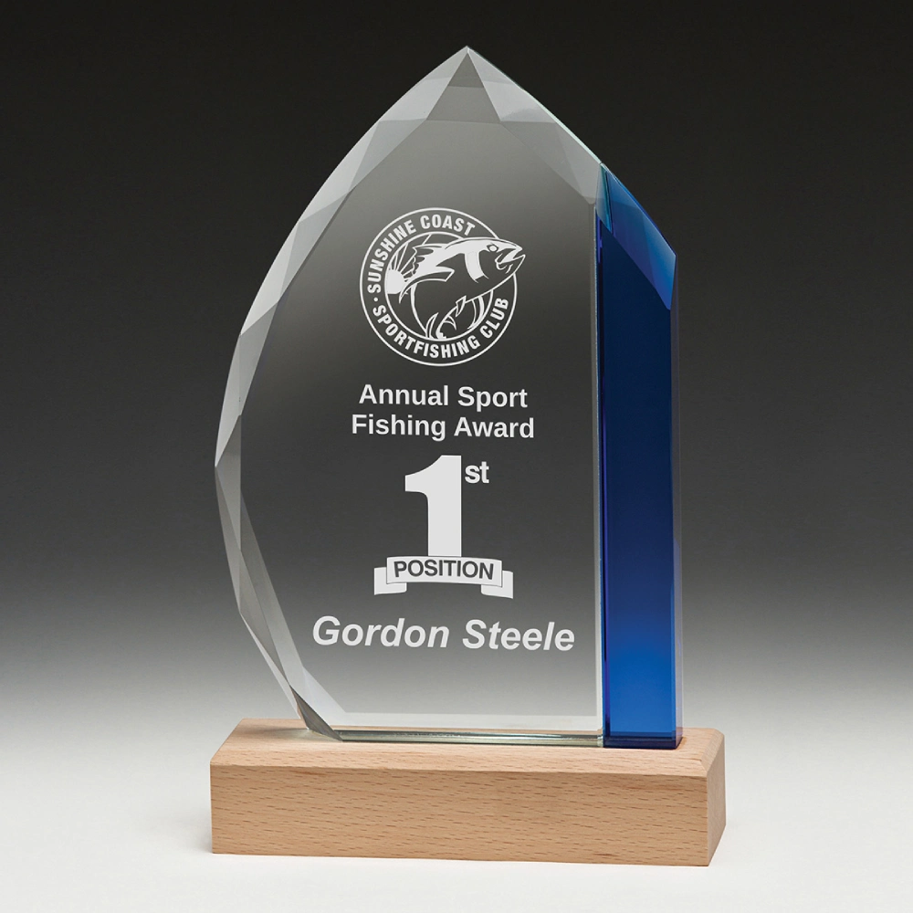Faceted clear and blue glass corporate awards trophy with engraved fishing award text mounted on natural timber base