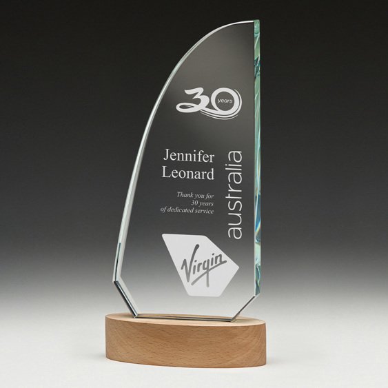 Sail shaped clear glass corporate awards trophy with engraved service recognition text mounted on round timber base