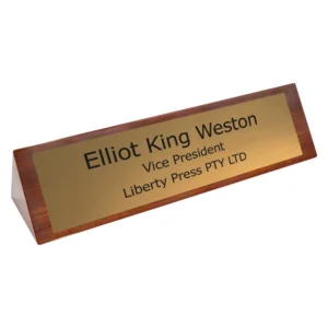 Angled timber desk name plate with engraved brass plate showing name and job title